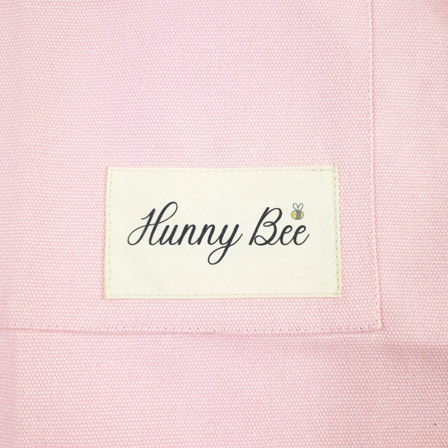 Closer up picture of Child apron, has Hunny Bee print with a small bee above the letter "e"