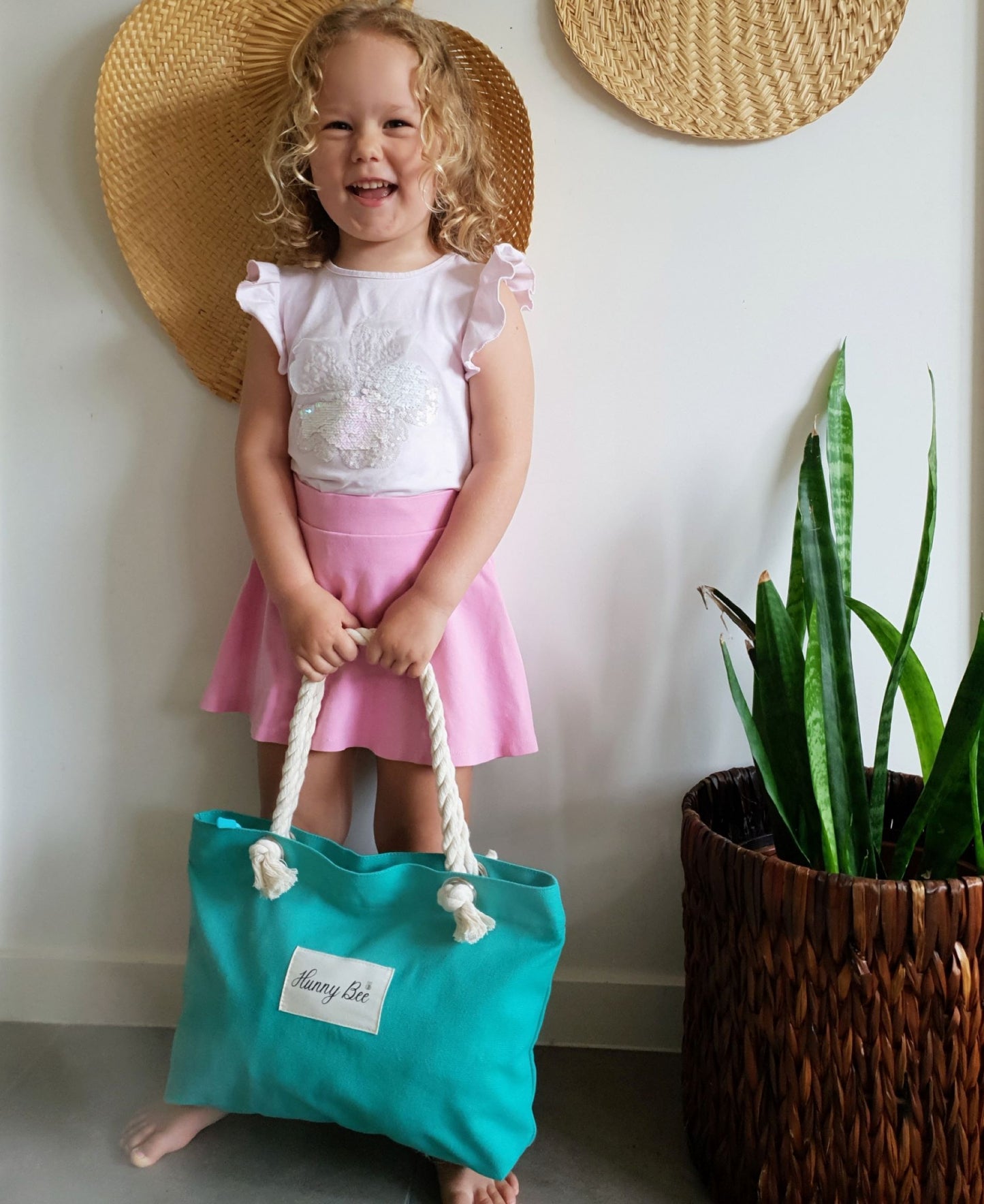 Girl holding Teal colour Tote bag, Tote bag has Hunny Bee print with a small picture of a bee, 100% organic cotton